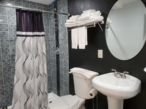 a bathroom with a toilet and a sink and a mirror at PineCrest Inn & Suites in Flagstaff