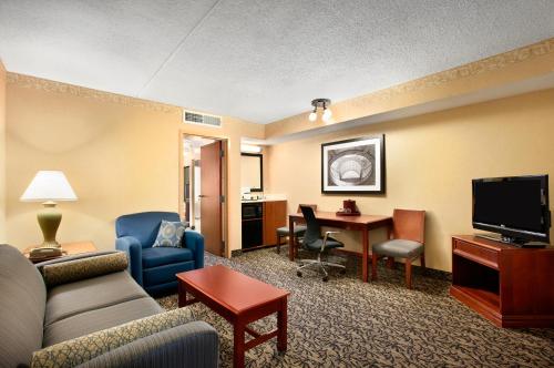 a living room with a couch and a desk with a television at Capitol Plaza Hotel Jefferson City in Jefferson City