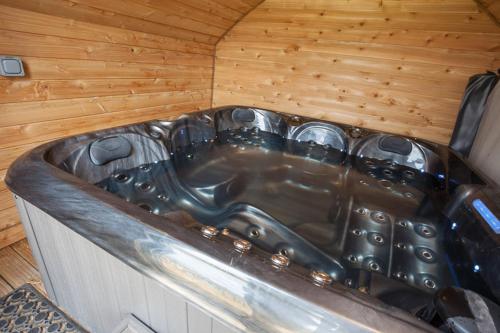 a bath tub in a room with a wooden wall at Tigh Beag na h'aibhne in Broadford