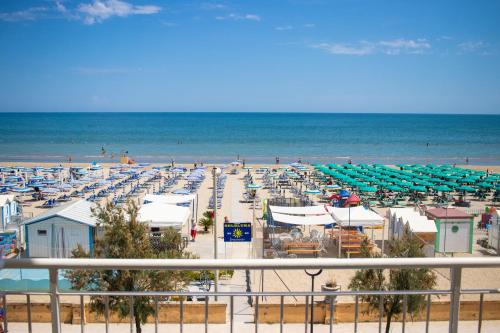 a beach with chairs and umbrellas and the ocean at Hotel B&B Sole in Senigallia