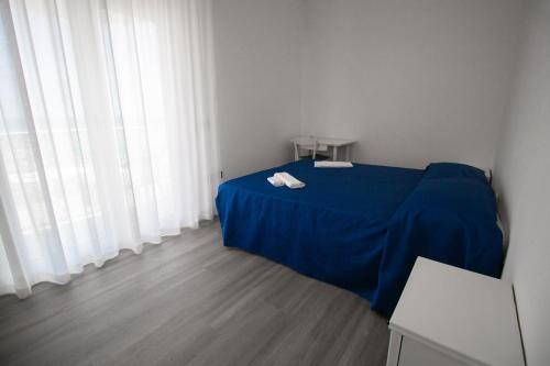 een kamer met een bed met een blauwe deken en gordijnen bij Hotel B&B Sole in Senigallia