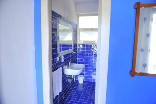 W wyłożonej niebieskimi kafelkami łazience znajduje się umywalka i toaleta. w obiekcie Apartment- Type A w mieście Baia Domizia