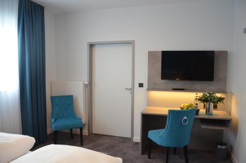 a hotel room with a desk and two blue chairs at Hotel Garni Nordseejuwel in Horumersiel