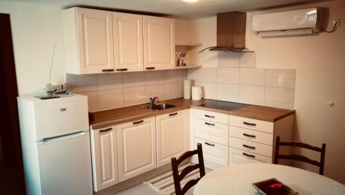 cocina con armarios blancos y nevera blanca en Quiet getaway house en Sečovlje