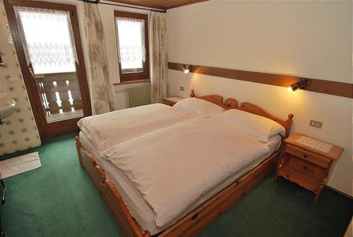 um quarto com uma cama grande e uma cabeceira em madeira em Appartamento trilocale nr. 5 em Livinallongo del Col di Lana