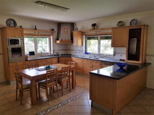 a kitchen with wooden cabinets and a table and chairs at Casa da Floresta in Santiago da Guarda