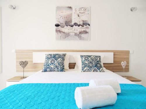 una camera da letto con un grande letto con cuscini blu e bianchi di Luz Apartments a Portimão