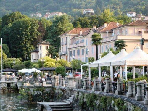 a town with buildings and a river with tables and chairs at Baveno mono in Baveno