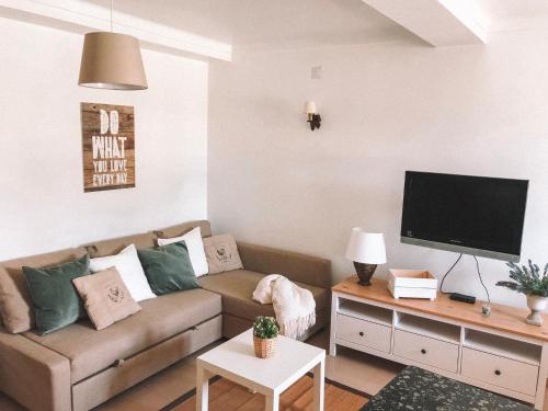 uma sala de estar com um sofá e uma televisão de ecrã plano em Casas do Lago em Estremoz