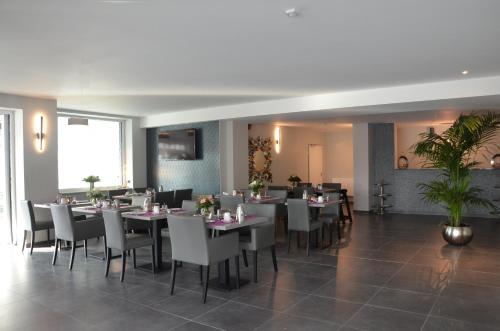 a dining room with tables and white chairs at Hotel Garni Nordseejuwel in Horumersiel
