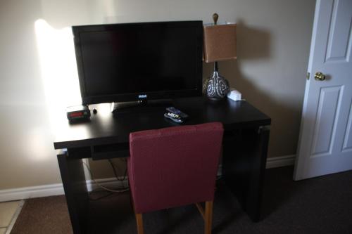 a desk with a monitor and a red chair at Kent Motel in Chatham