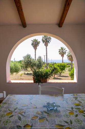 a dining room with a table and a window with palm trees at Residenza il Normanno - La terrazza sul mare in Santa Domenica