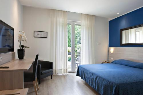 una camera con letto blu, scrivania e computer di Hotel Garibaldi a Padova