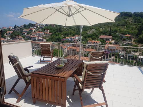 een houten tafel en stoelen met een parasol op een balkon bij New Apartment with panoramic view in Stomorska