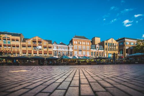 a city square with buildings and tables and chairs at Queen Hotel in Eindhoven