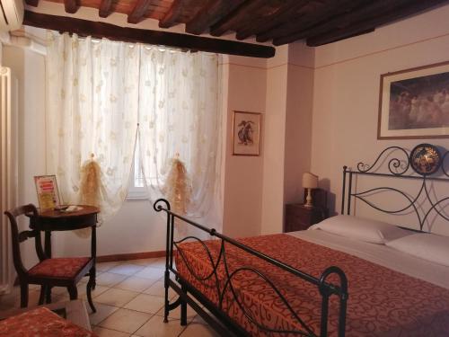 a bedroom with a bed and a table and a window at B&B Alle Due Porte in Siena