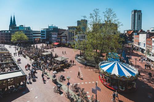 a busy city street with people and a carousel at Queen Hotel in Eindhoven