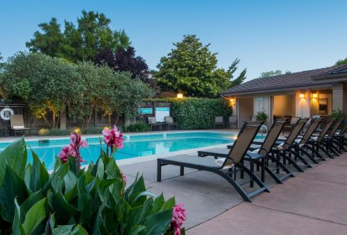 a swimming pool with chairs next to a house at El Pueblo Inn in Sonoma