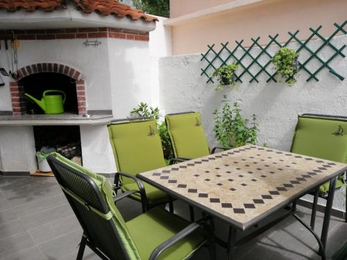 une table et des chaises sur une terrasse avec une cheminée dans l'établissement Apartmani Marinović, à Podgora