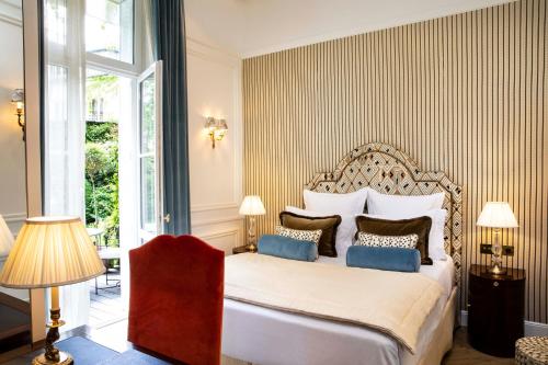 a bedroom with a large white bed with blue pillows at Relais Christine in Paris
