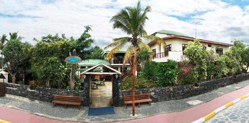 a building with two benches and a palm tree at Hotel San Vicente Galapagos in Puerto Villamil