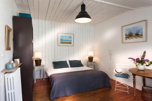 ein Schlafzimmer mit einem Bett, zwei Tischen und einer Lampe in der Unterkunft La Venelle de Jéricho in La Rochelle