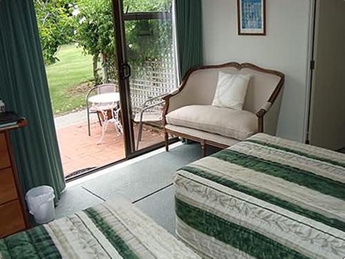 a bedroom with a bed and a chair and a patio at Warkworth Country House in Warkworth