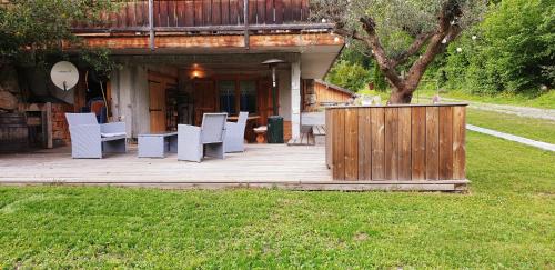 eine Holzterrasse mit weißen Stühlen und einem Gebäude in der Unterkunft Entre Giffre et Valentine in Verchaix