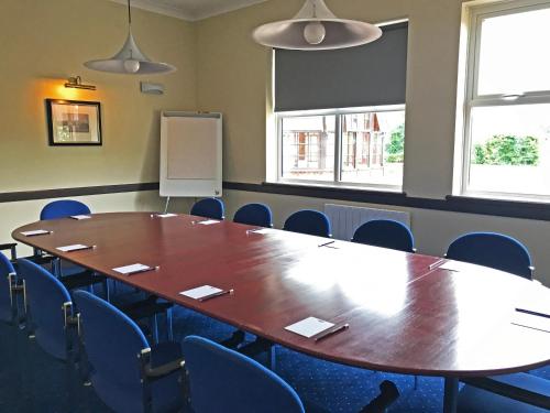 a conference room with a large wooden table and chairs at Dragonfly Hotel Colchester in Colchester