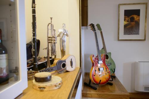 uma prateleira com guitarras e um liquidificador em Casa da Amendoeira em Castelo Rodrigo