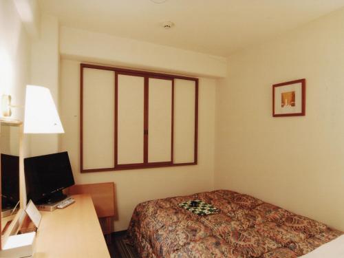 a hotel room with a bed and a desk with a computer at Kuretake-Inn Hamamatsu Nishi I.C. in Hamamatsu