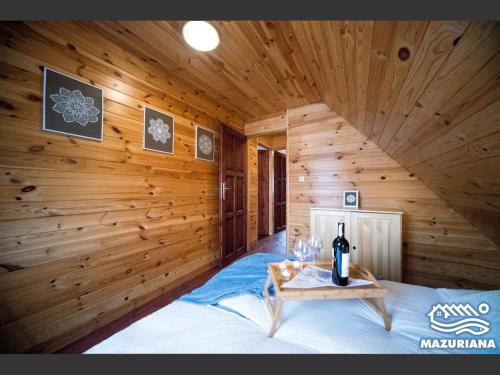 a room with a bed with a bottle of wine on a table at Mazuriana - domy wypoczynkowe nad jeziorem in Skomack Wielki