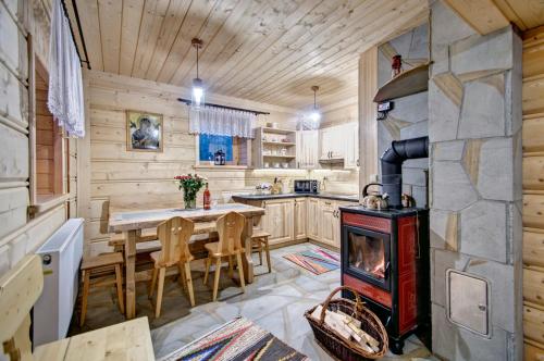 a kitchen and dining room with a fireplace in a log cabin at Jędroskowe Chatki in Witów