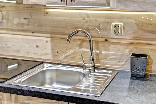 a stainless steel sink in a kitchen with wooden walls at Jędroskowe Chatki in Witów