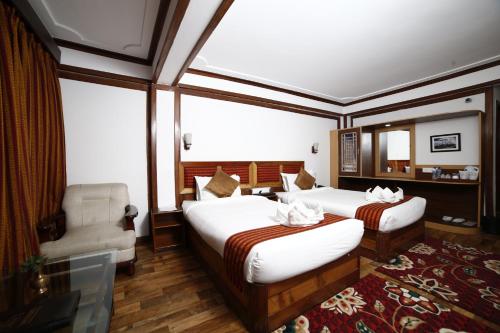 a hotel room with two beds and a chair at Sikkim Tourist Centre in Pelling