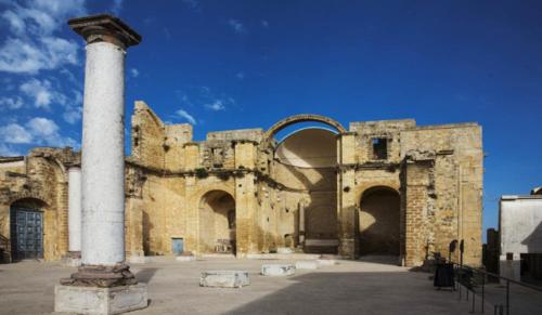 an old stone building with a column and a pole at La Giummara Rooms in Salemi