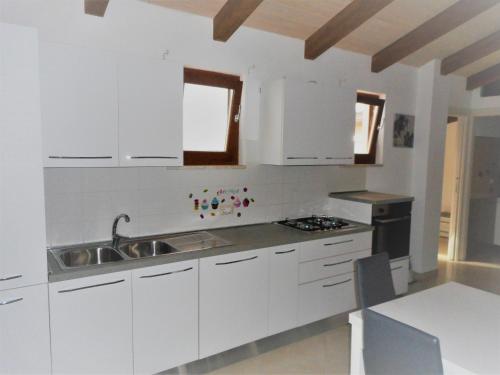 una cocina con armarios blancos y fregadero en Giulia, en Gaeta
