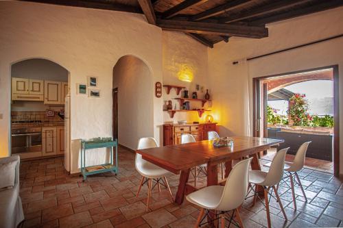 uma cozinha e sala de jantar com uma mesa de madeira e cadeiras em Villa Kalè - Klodge em Olbia