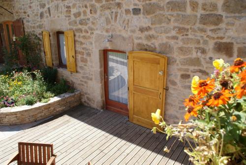 a wooden door in a stone building with flowers at Les Caselles, Gîte et Chambre d'hôtes in Saint-Beauzély