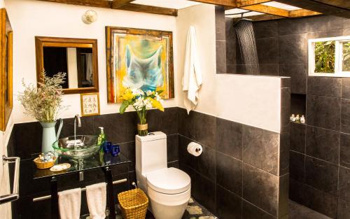 a bathroom with a white toilet and a black tile wall at La Colina Hotel Cottage in Bogotá