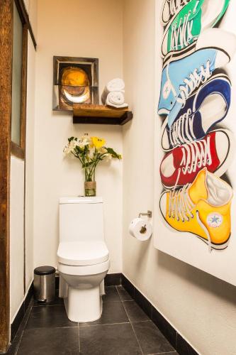 a bathroom with a toilet with shoes on the wall at La Colina Hotel Cottage in Bogotá