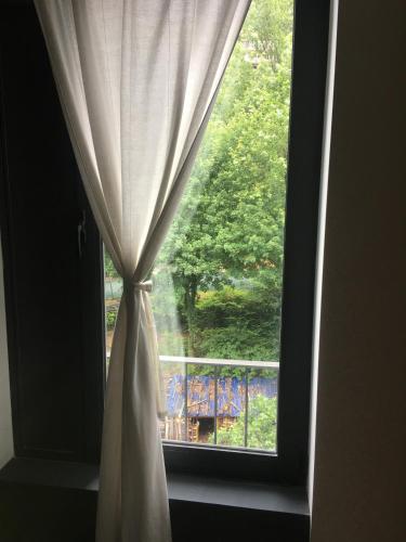 a window with a curtain and a view of a balcony at The River's Whisper Apartment in Geres