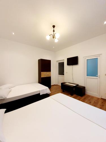 a white bedroom with a bed and a tv at Casa Eduard in Eforie Sud