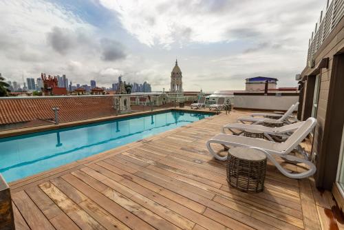 a deck with chairs and a swimming pool on a building at Central Hotel Panama Casco Viejo in Panama City