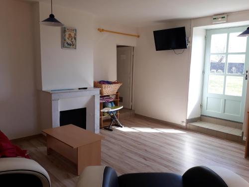 a living room with a fireplace and a tv at Maison de la Monne in Olloix