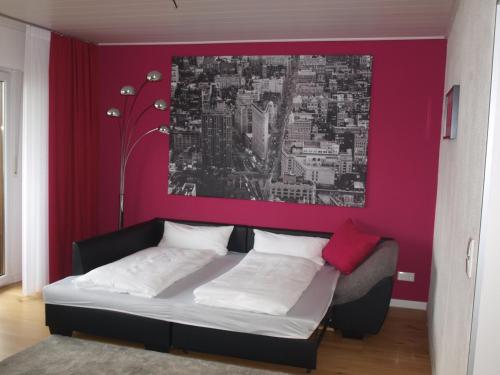une chambre avec un lit avec un mur rose dans l'établissement SC Apartment - Nürnberg Messe / Fränkisches Seenland, à Schwabach
