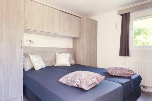een slaapkamer met een blauw bed met 2 kussens bij Korhoen 4 persons in Rijssen