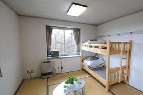 a room with two bunk beds and a window at Kusatsu Kogen Youth Hostel in Kusatsu