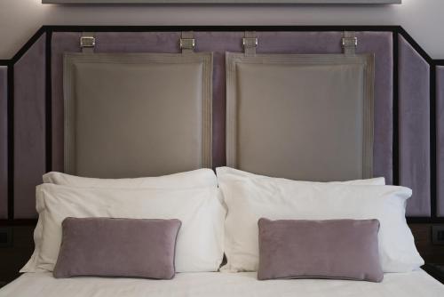 a bed with white pillows and a purple headboard at Solo Experience Hotel in Florence