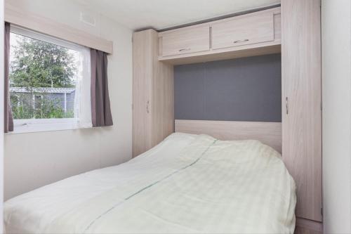 1 dormitorio con cama y ventana en MB Zeeuwse Mobile Home, en Hoek